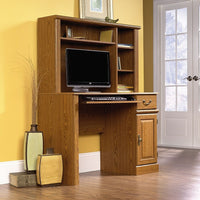 Orchard Hills - Bureau informatique avec bahut, chêne de Caroline-Le bureau informatique avec bahut de Orchard Hills comporte une tablette coulissante pour clavier/souris avec glissières en métal et butées de sécurité et un tiroir spacieux qui comprend le système d’assemblage breveté T-lock